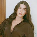 Model in a brown satin shirt wearing the Pear Dangle Diamond Necklace in 14K solid gold