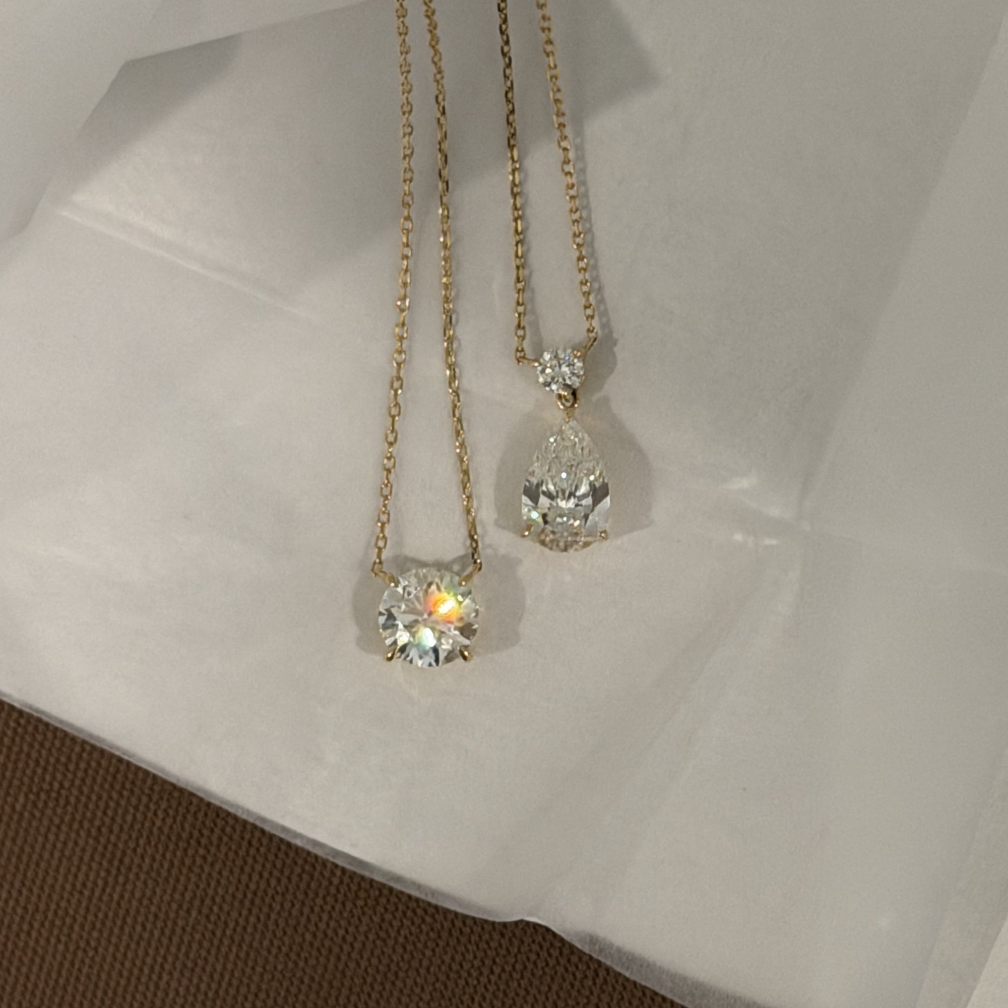 Two Pear Dangle Diamond Necklaces in 14K solid gold with IGI Certified Lab Diamonds on white linen