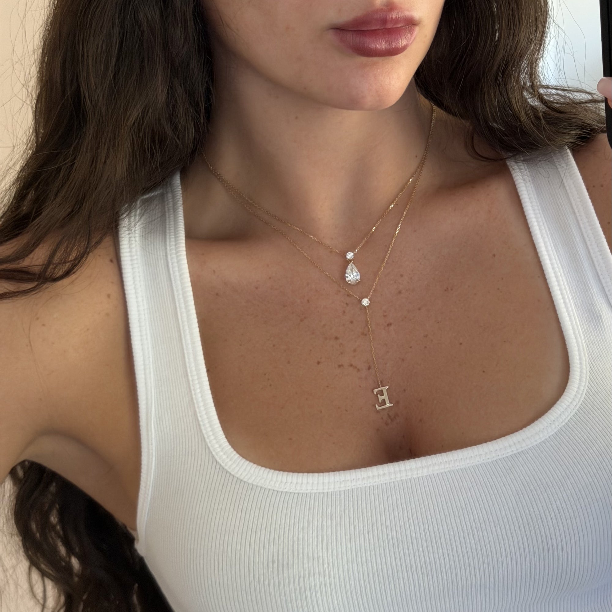 Pear Dangle Diamond Necklace layered with a letter necklace, worn with a white tank top