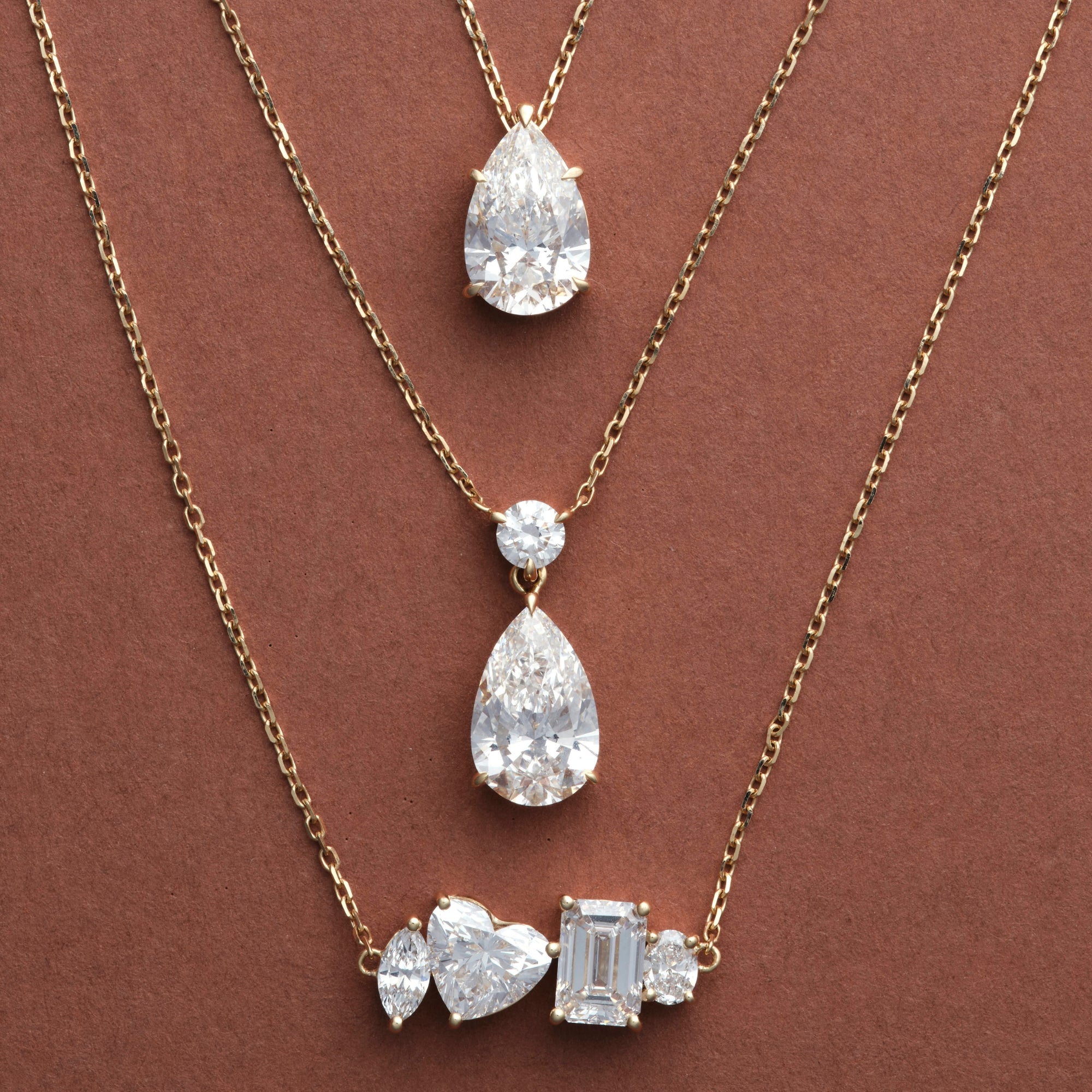 Pear Dangle, Classic Pear and Multi Shape Diamond Necklaces in 14K solid gold on a brown background