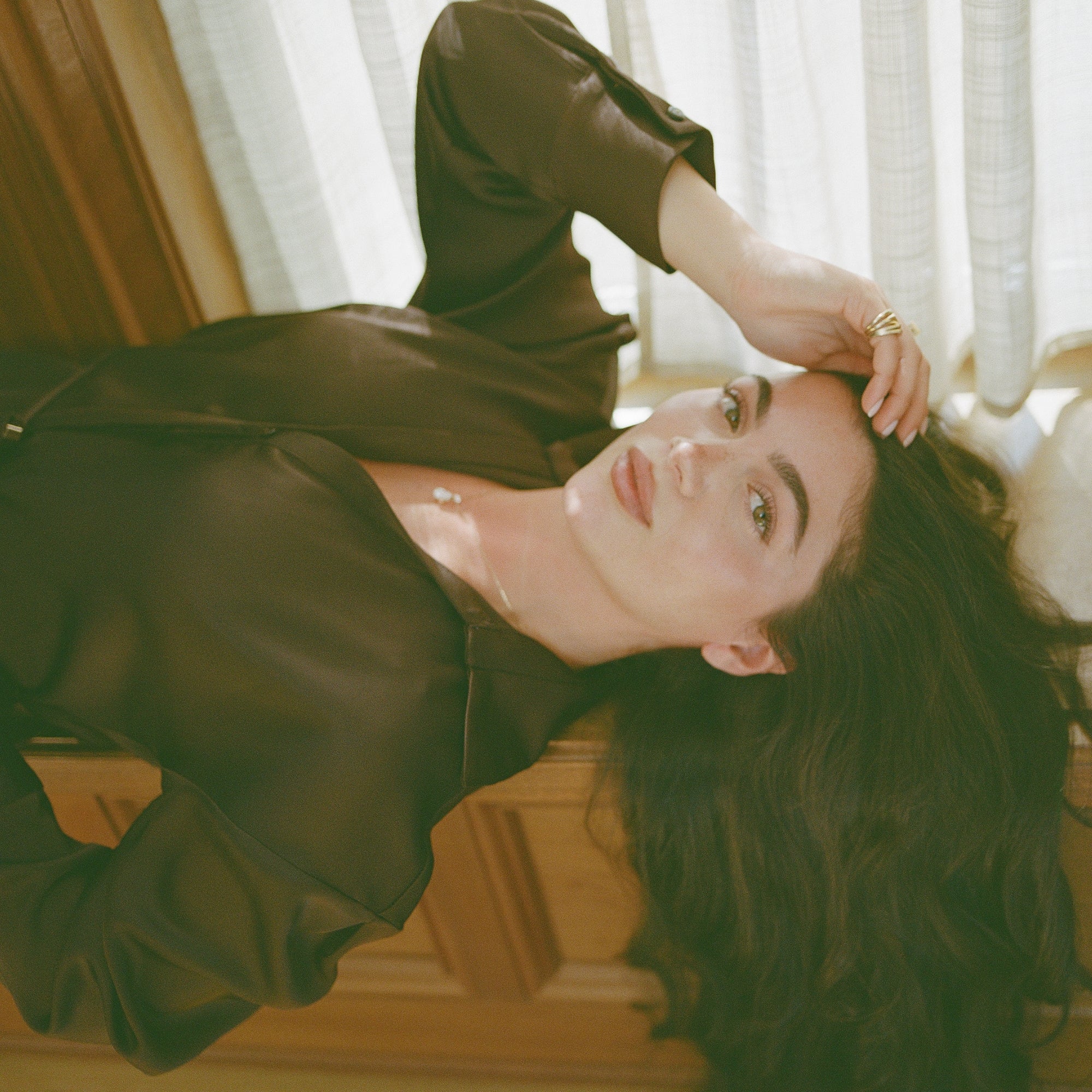 Model lying back in a brown satin outfit wearing the 14K solid gold Pear Dangle Diamond Necklace