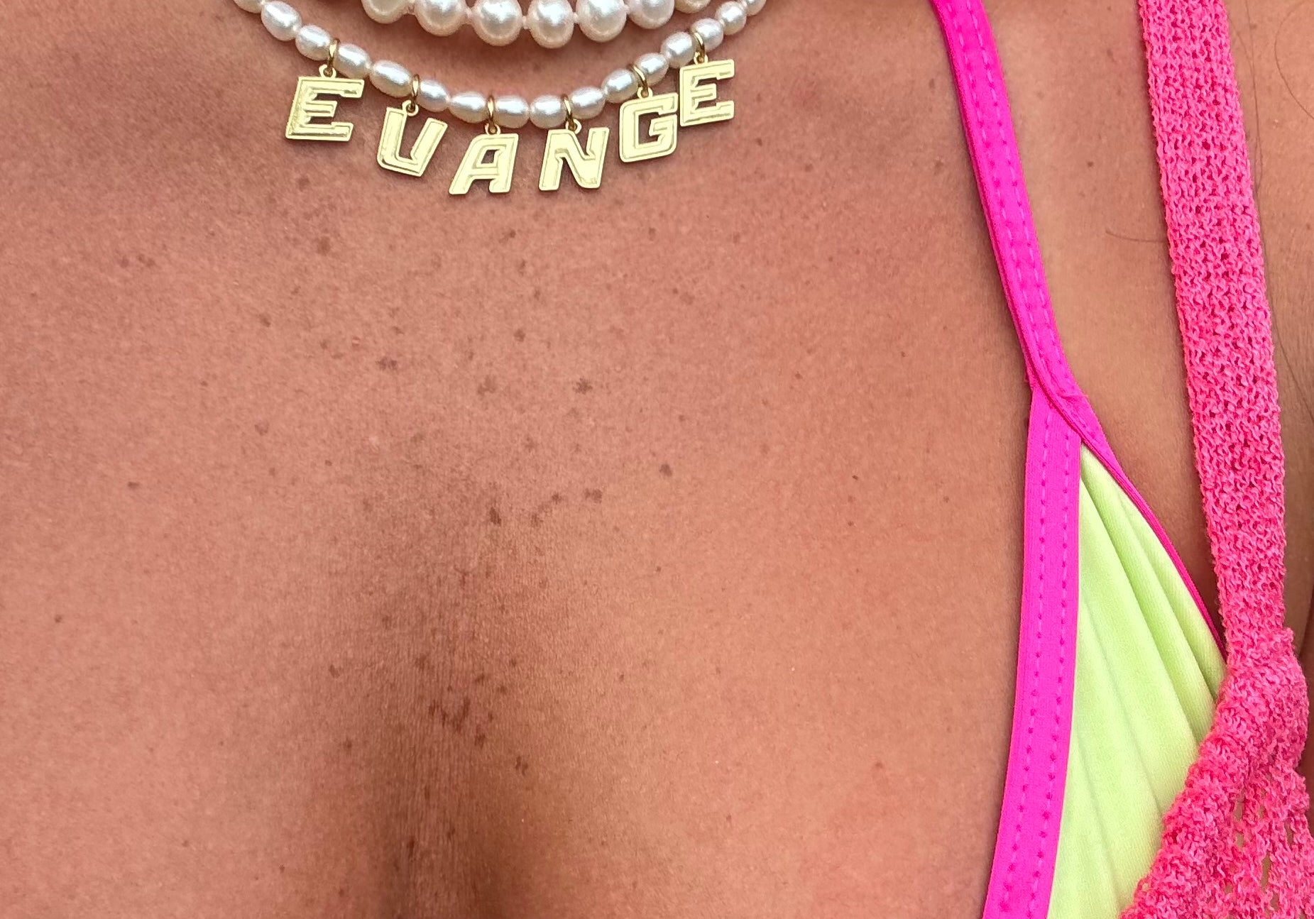 Pearly Nameplate Necklace in EVANGE layered with pearl strands and a pink bikini top