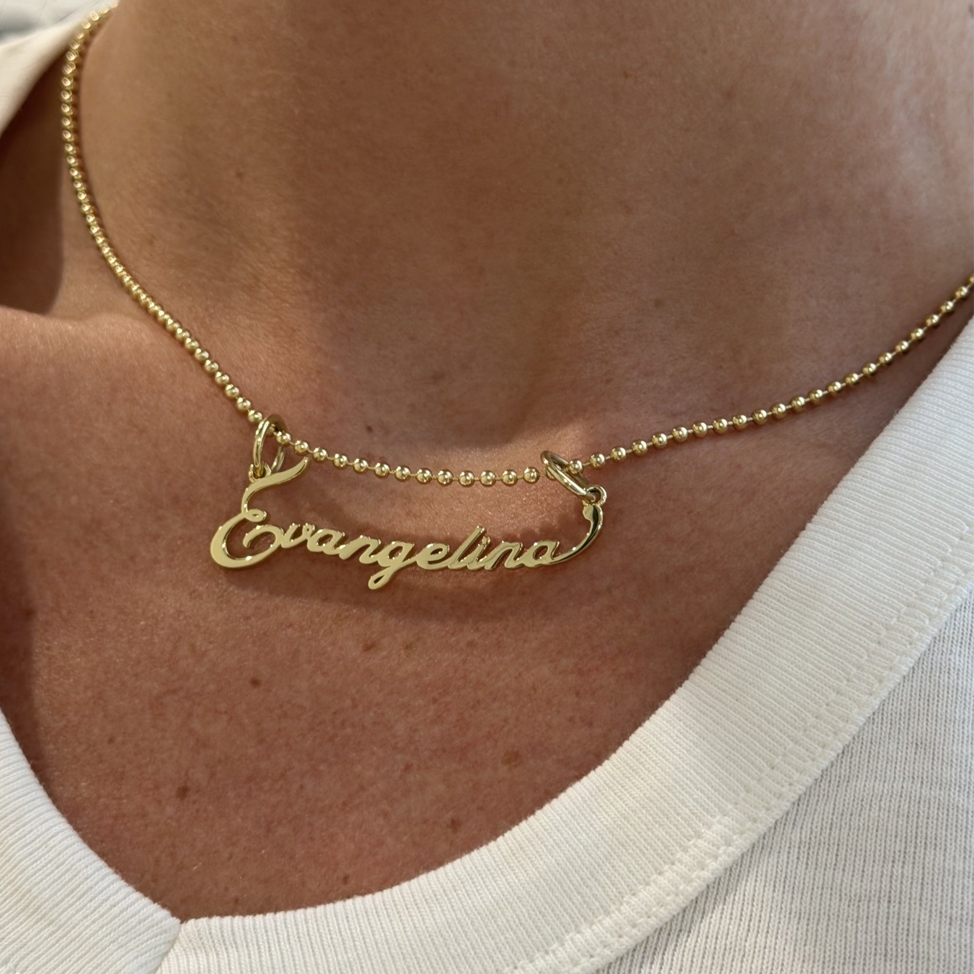 Close-up of the Signature Script Nameplate Charm spelling Evangelina