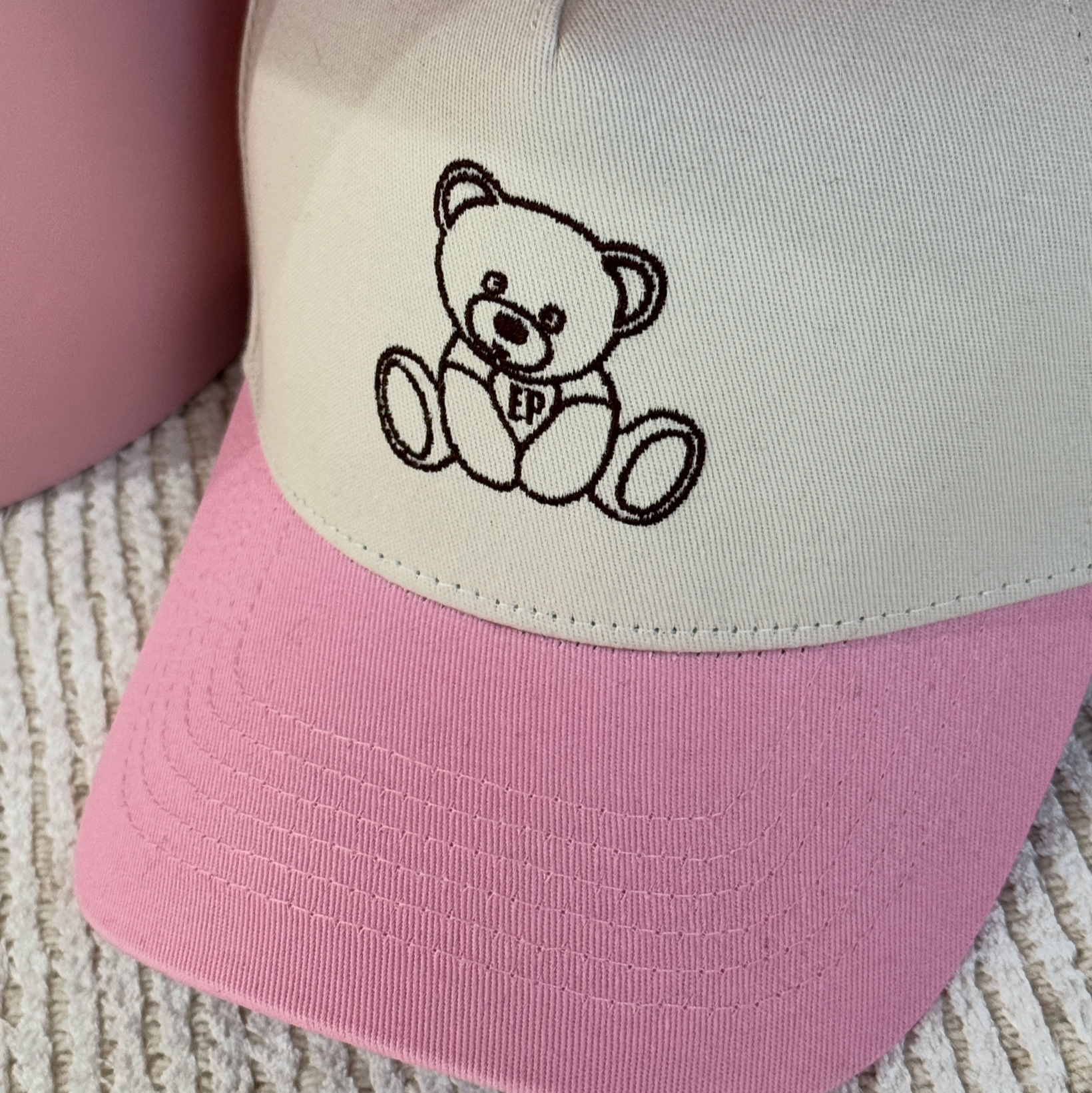 Close-up of the embroidered teddy bear on the pink EP Teddy Trucker Hat
