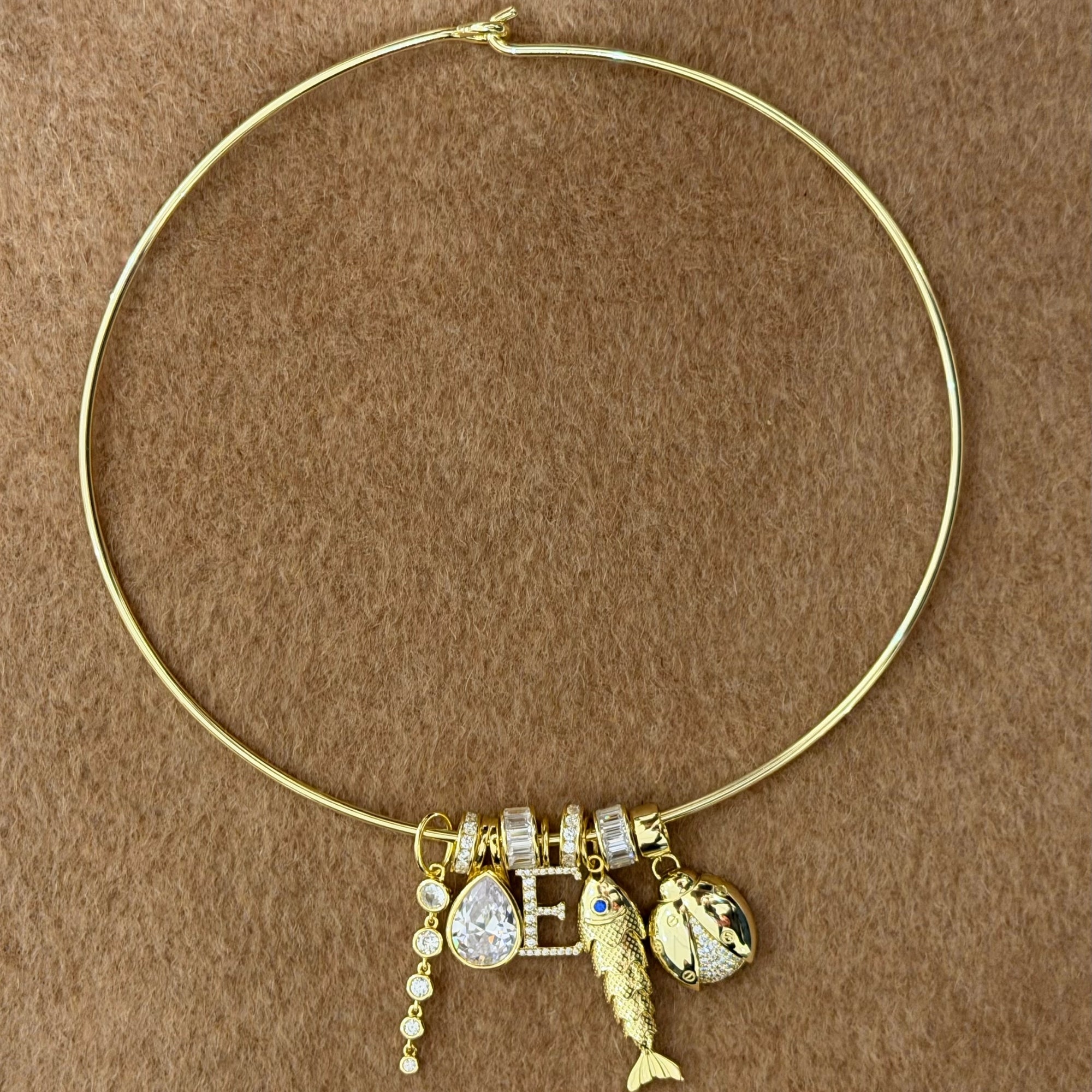 Thin gold cuff necklace stacked with CZ slider charms and pendant charms