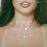 Close-up of the Timeless Lariat Letter Necklace layered with diamond necklaces, 14K solid gold